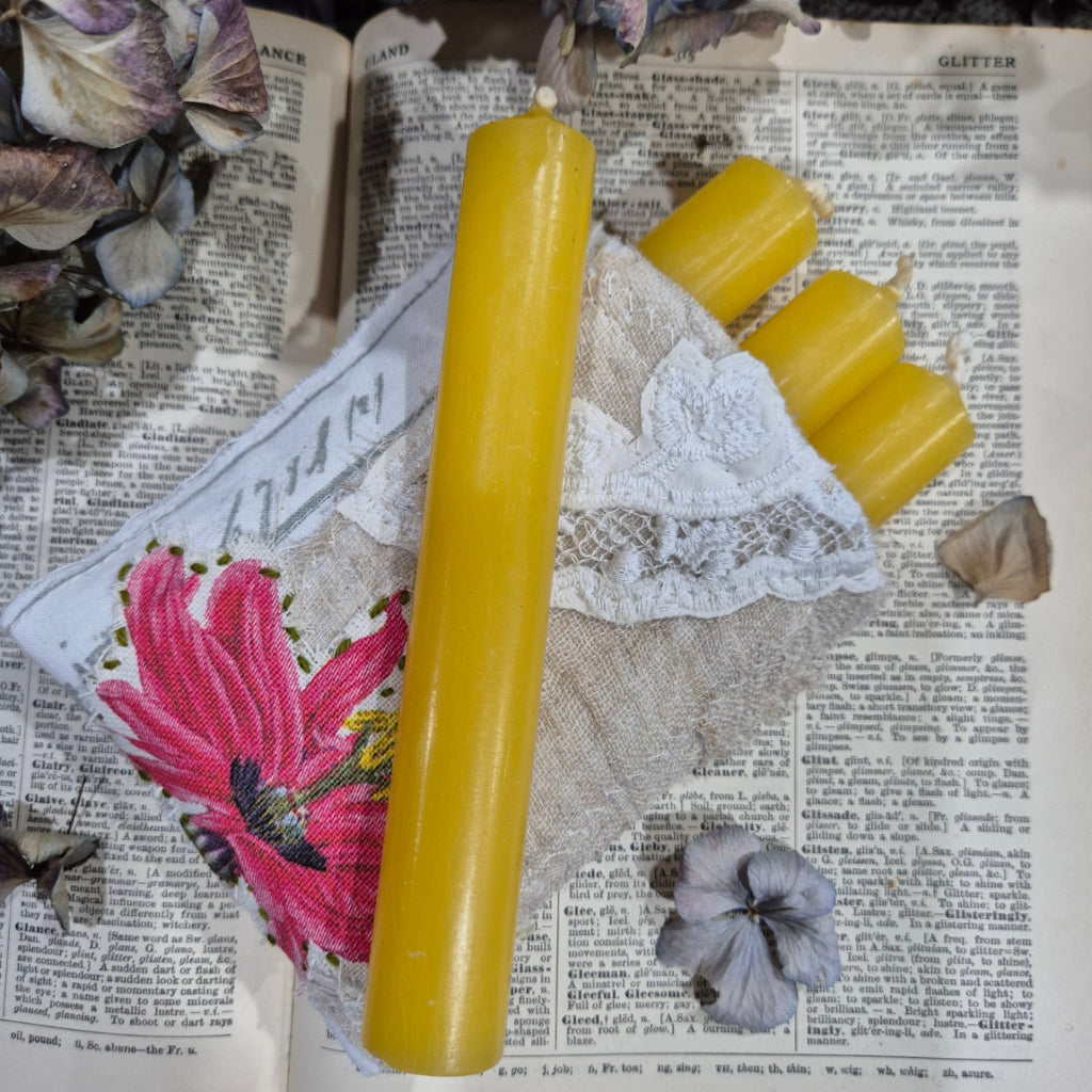Three yellow candles on an open book with flowers and fabric
