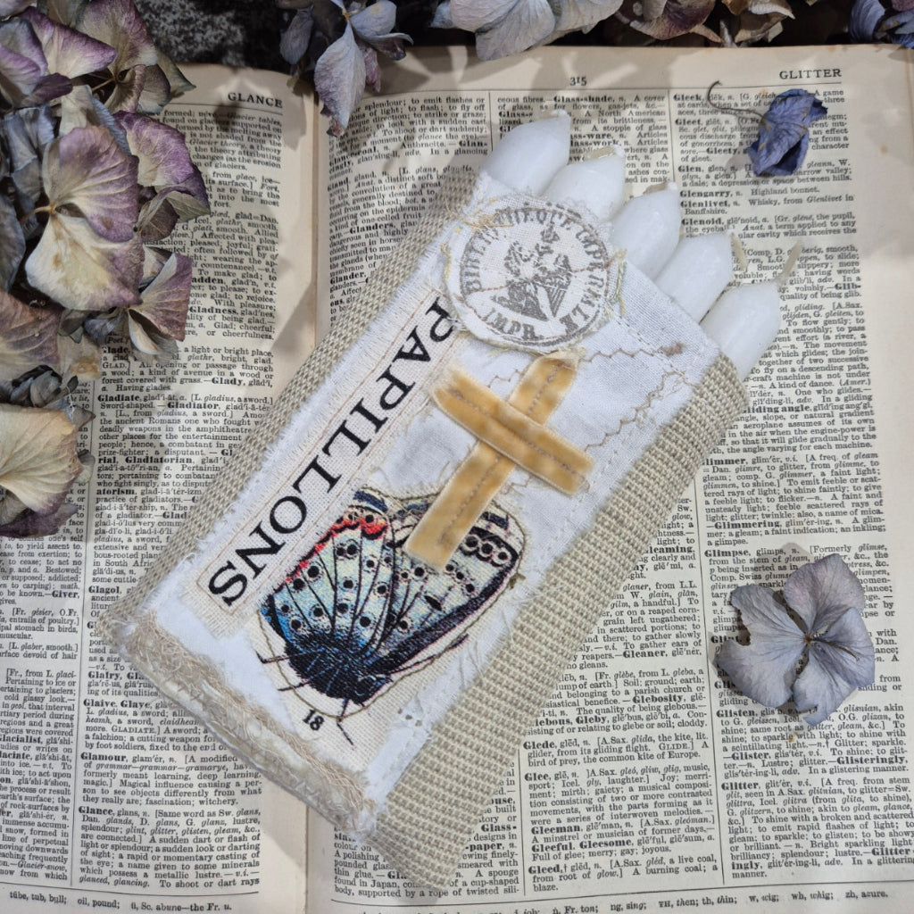 Decorative fabric bag with butterfly design and 'Papillons' text on a textured surface with flowers.