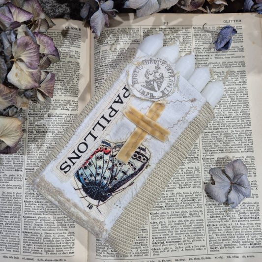 Decorative fabric bag with butterfly design and 'Papillons' text on a textured surface with flowers.