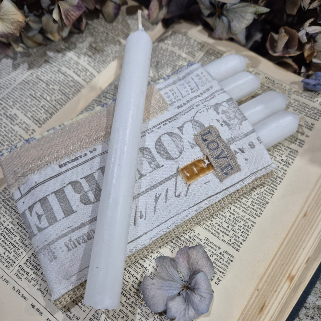 White candles on a newspaper with a decorative box labeled 'LOVE'.