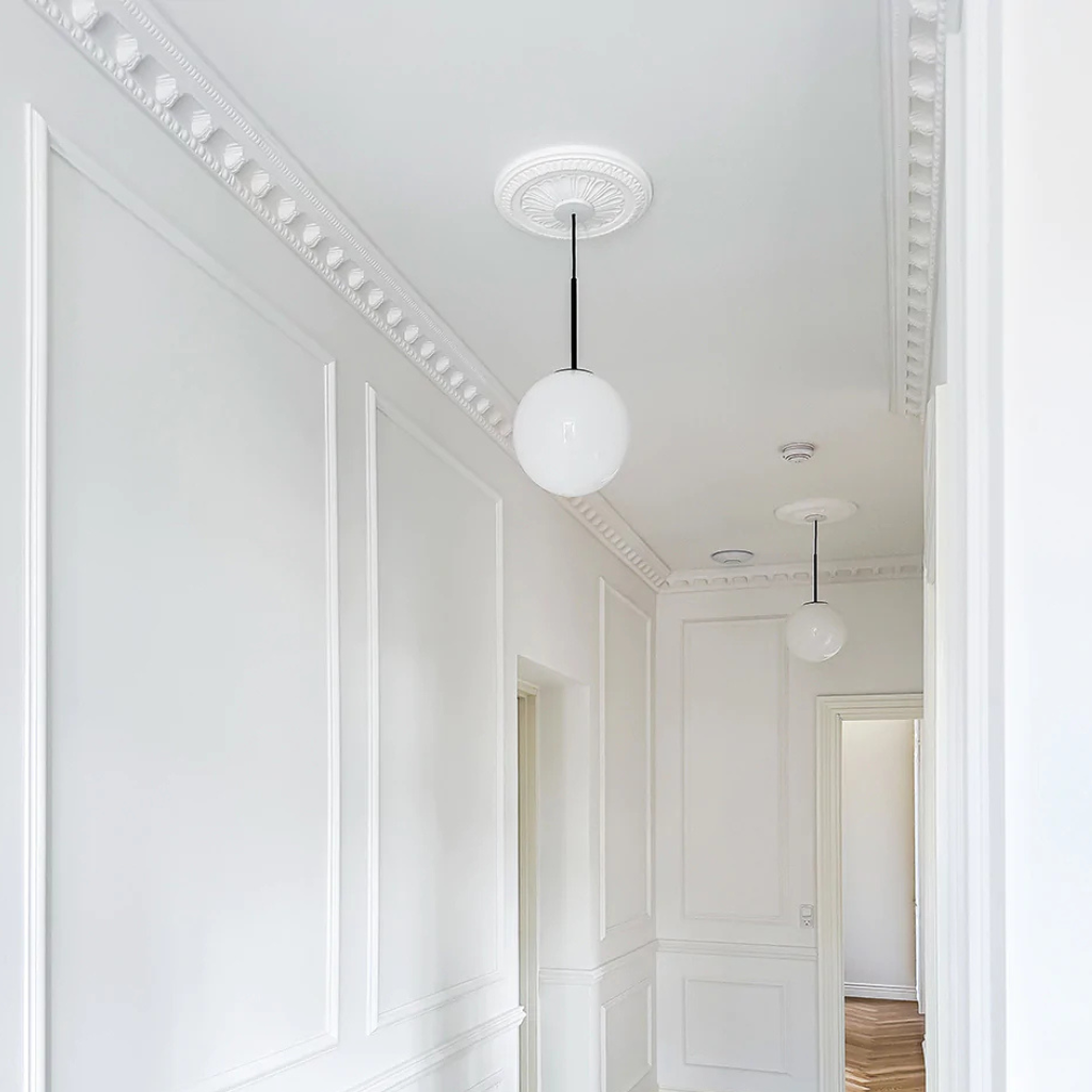 Modern pendant lights hanging in a stylishly decorated hallway with white walls and ceiling.