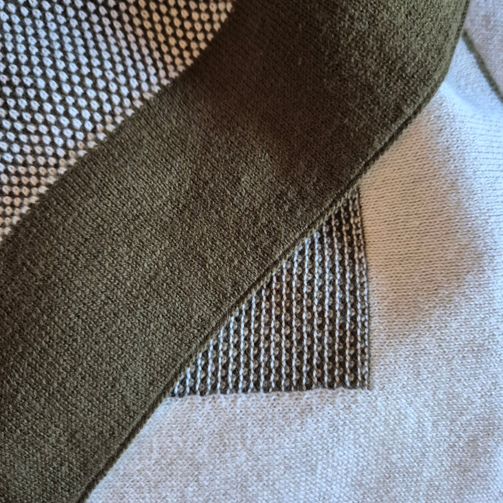 Close-up of a textured fabric with a green stripe on a checkered background
