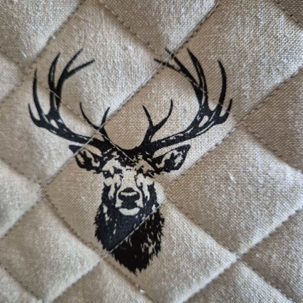 Black deer design on a quilted beige fabric background