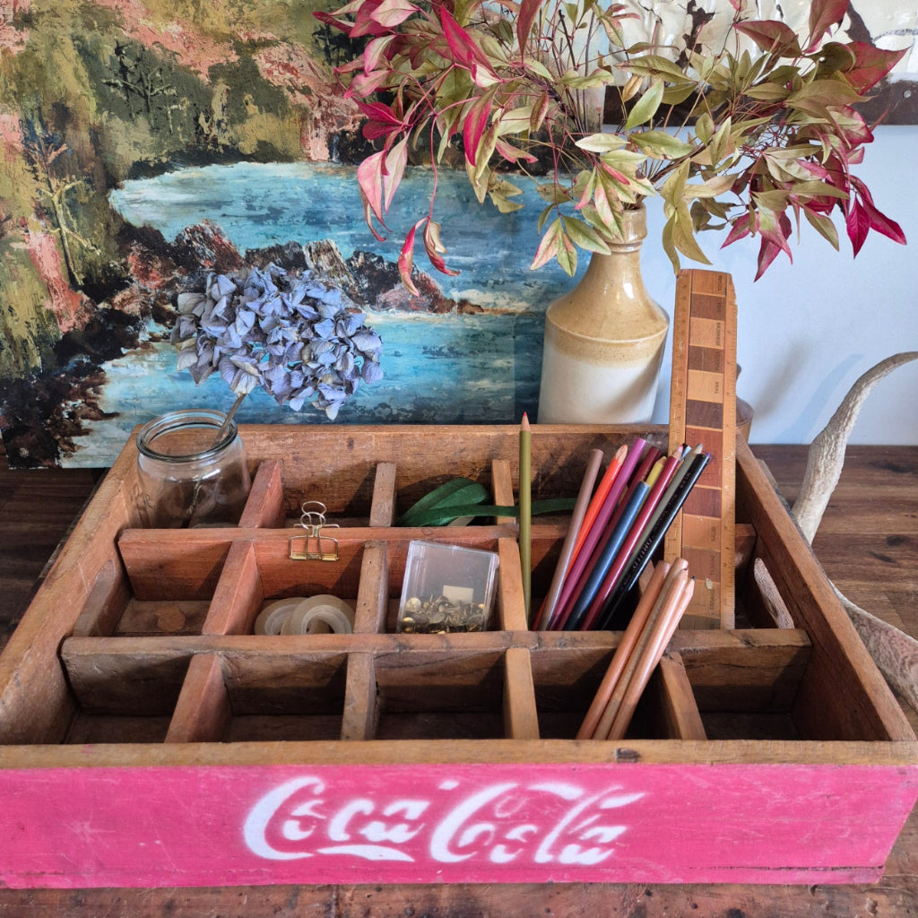Wooden tray with various items including a Coca-Cola sign, plants, and decorative objects.