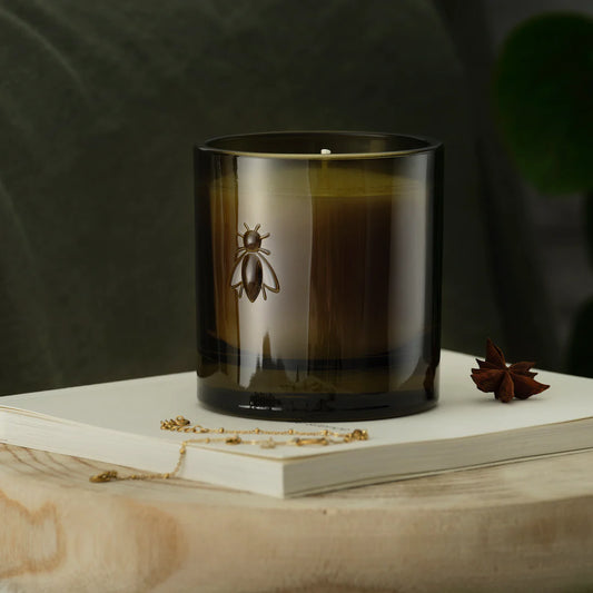 Candle with a bee design on a book against a dark background