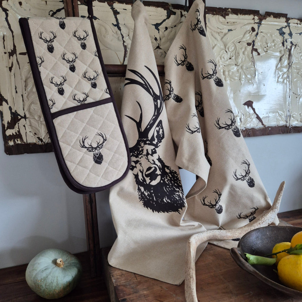 Pair of oven mitts with deer pattern on a wooden surface