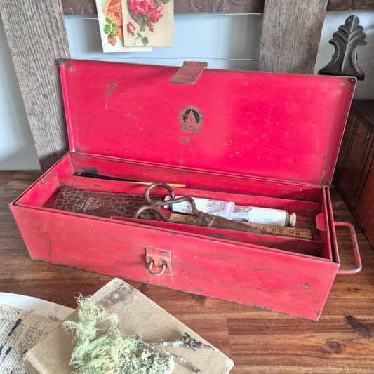 Open red metal tool box with tools inside on a wooden surface