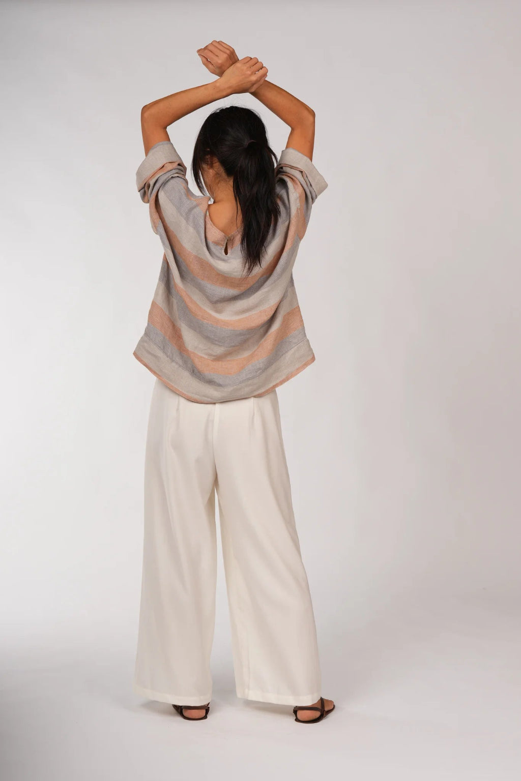 Woman wearing a striped sweater and wide-leg pants on a white background