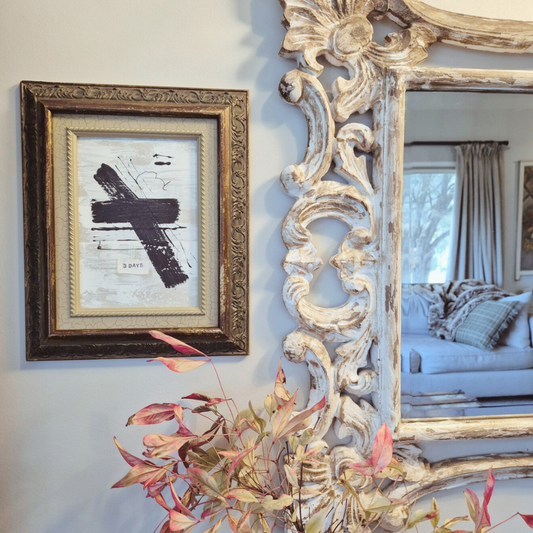 Decorative mirror with intricate designs next to a framed picture on a wall.