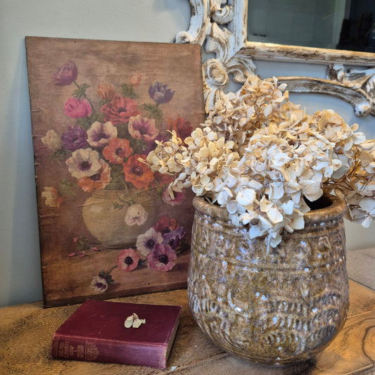 Decorative still life with flowers, vase, and painting on a surface