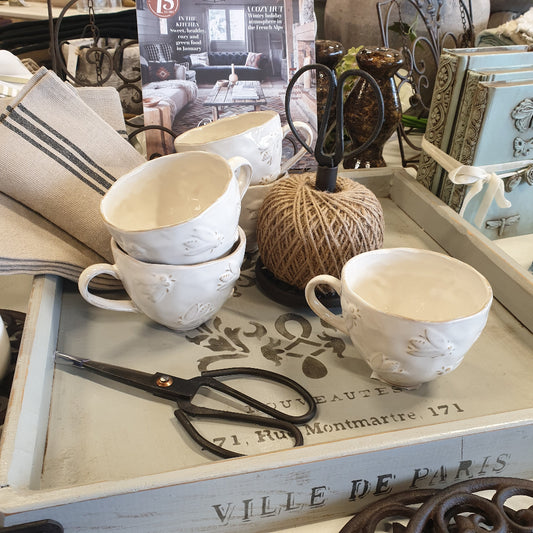 Rustic Country kitchen setting with cream ceramic cups, black scissors, and a string ball.