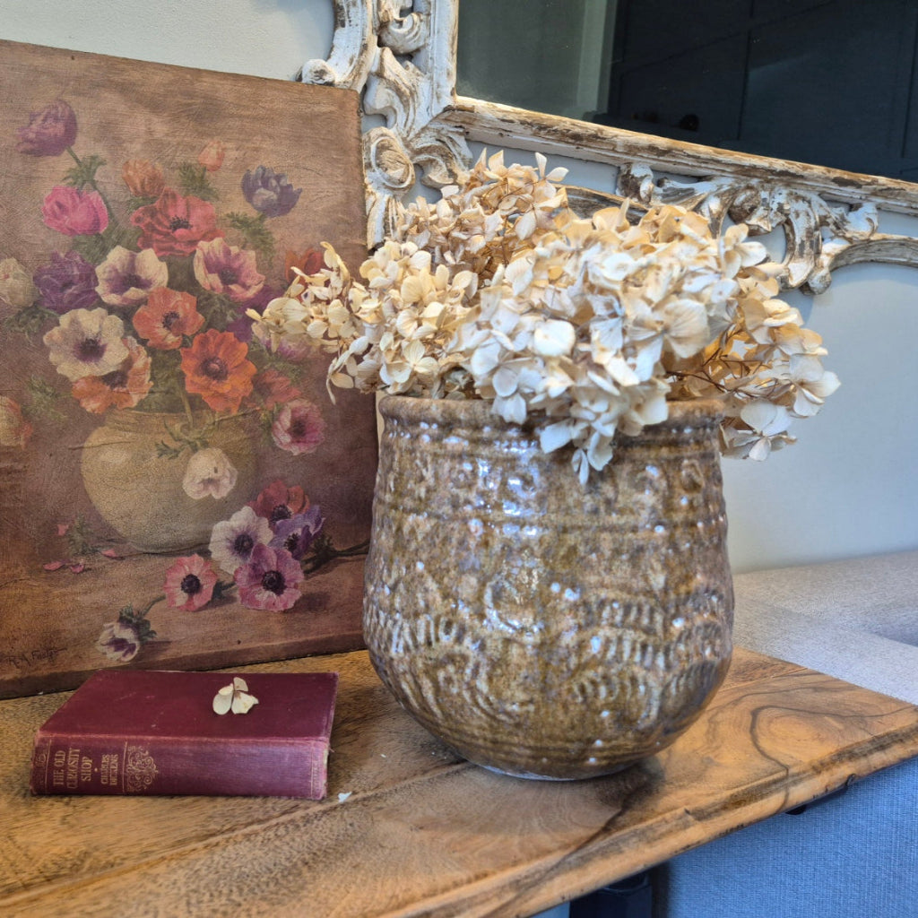 Decorative vase with flowers on a table next to a framed painting and book