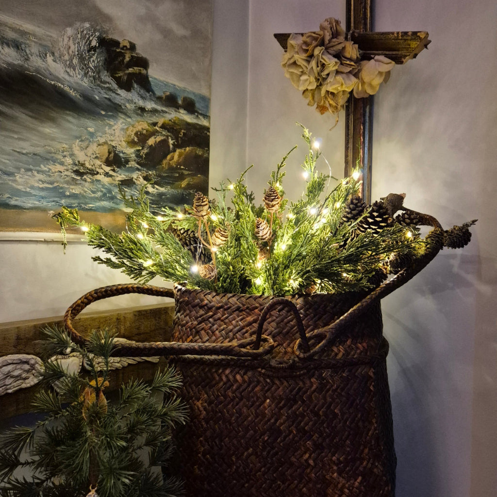 Decorative wreath with lights and pinecones on a textured surface