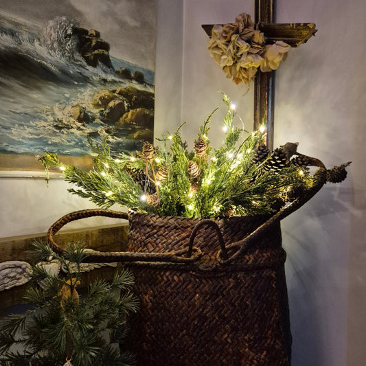 Decorative wreath with lights and pinecones on a textured surface