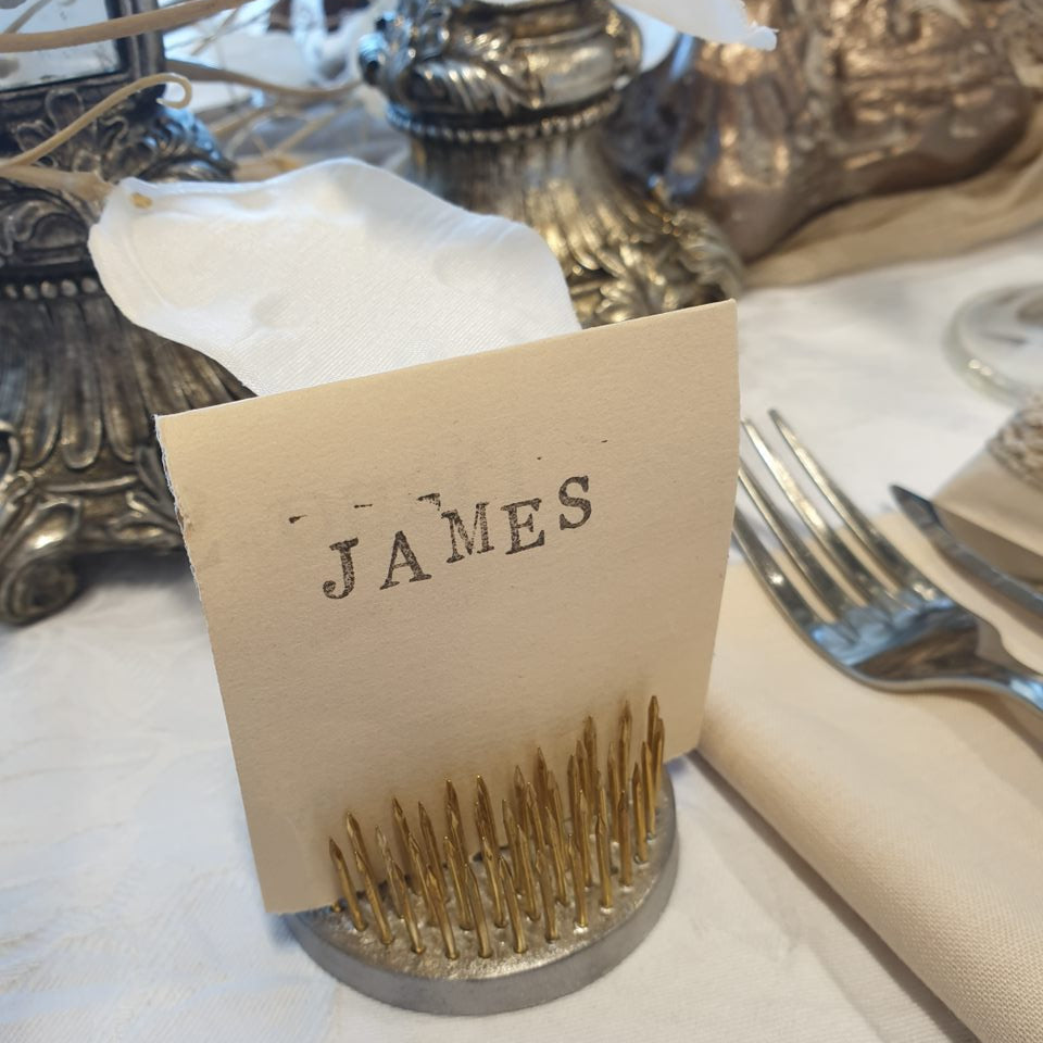 Frog Pin with 'JAMES' label on a white surface with silver platters in the background