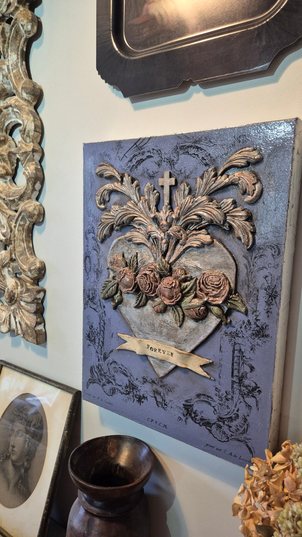 Decorative plaque with floral design and text on a white surface with decorative items.