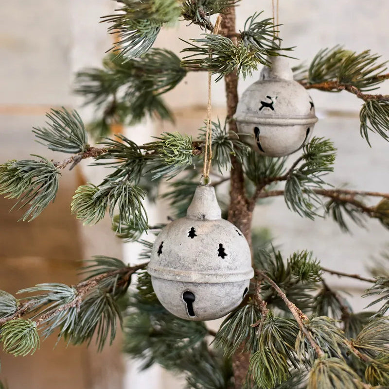 Decorative grey bells hanging on a Christmas tree branch.