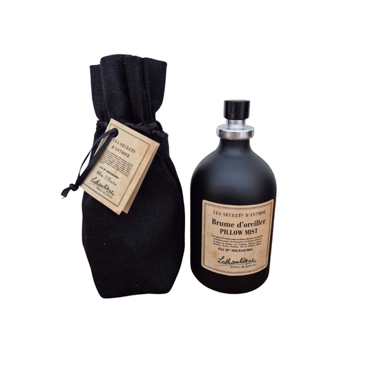 Black bottle of 'Brume d'oreiller' pillow mist with a black drawstring bag on a white background