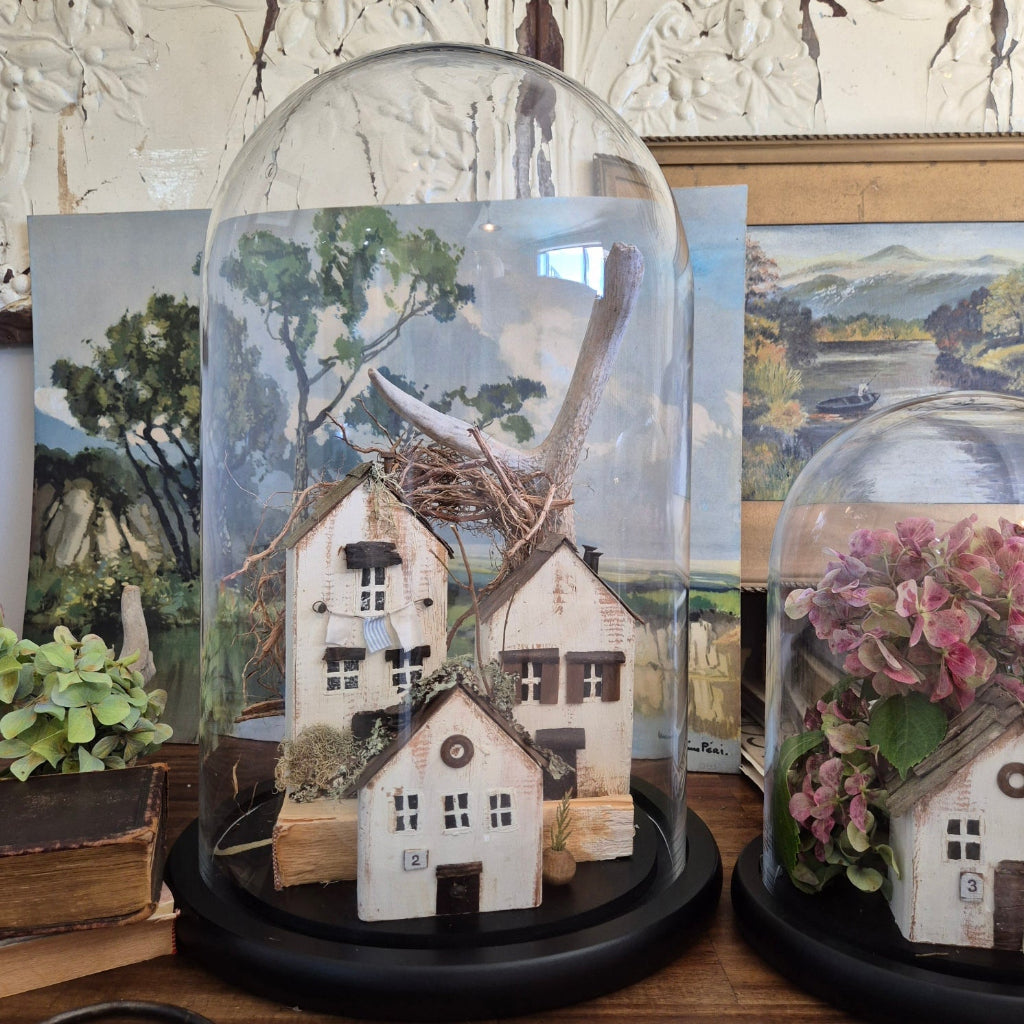 Decorative houses under glass domes on a table with nature-themed background