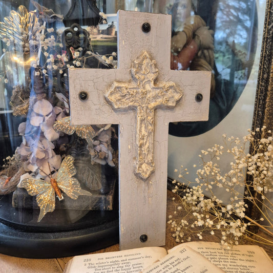 Decorative cross with gold detailing on a glass surface with flowers and text.