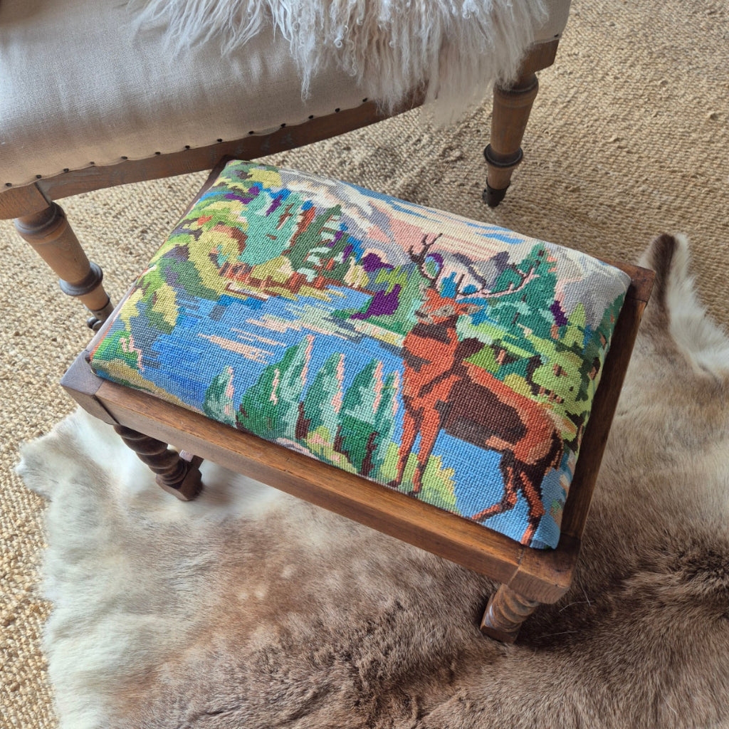 Decorative stool with a colorful needlepoint cushion on a textured surface