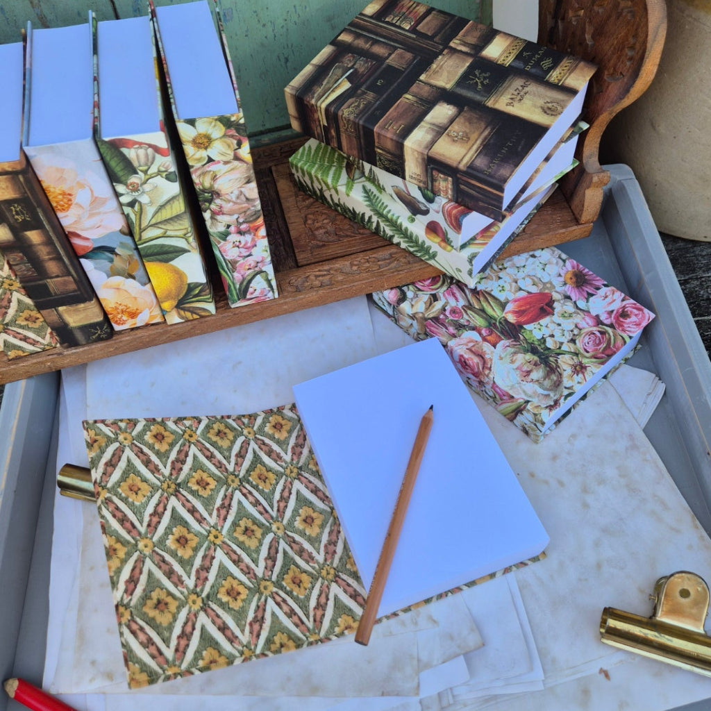 Decorative stationery items including patterned notebooks and cards on a wooden tray.