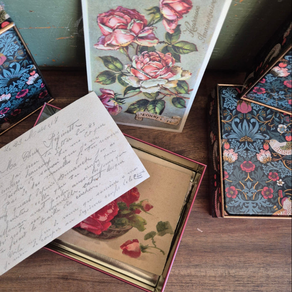 Vintage postcards with floral designs and handwritten text on a wooden surface