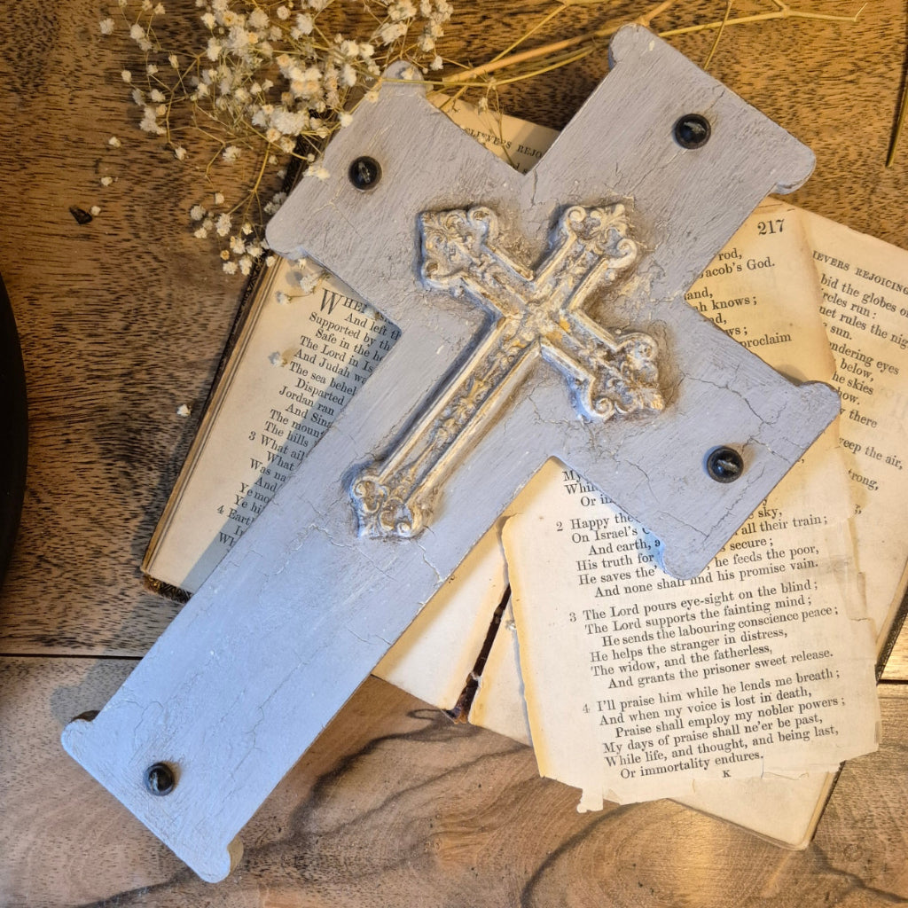 Decorative cross on a wooden surface with an old book underneath