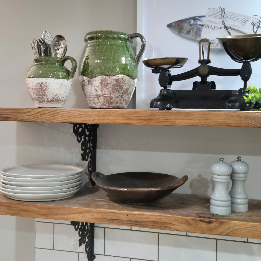 Wooden shelf with ceramic jars, a bowl, and salt and pepper shakers against a tiled wall.