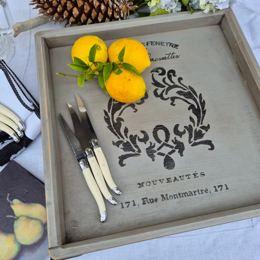 Decorative tray with lemons, cutlery, and a decorative design on a white surface.