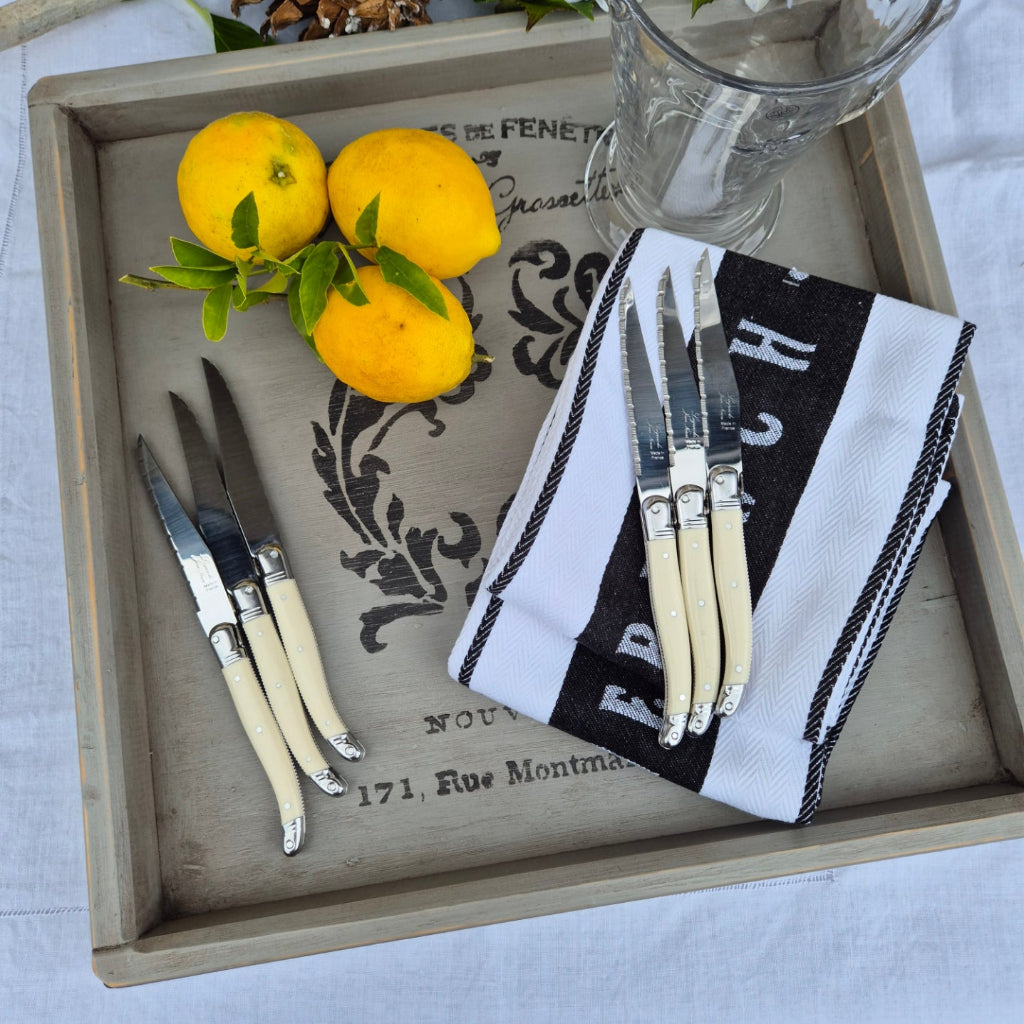 Wooden tray with cutlery, lemons, and a decorative cloth on a light background