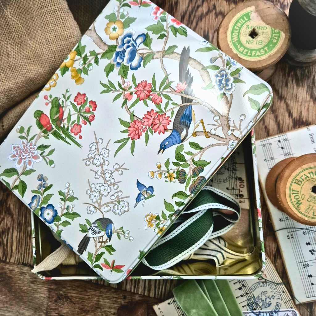 Floral and bird patterned notebook with ribbon on a wooden surface