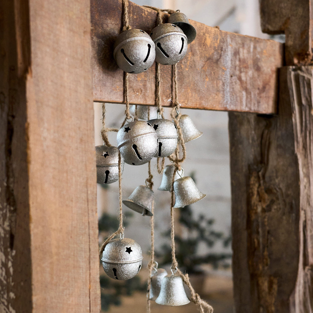 Decorative metal bells hanging on a rustic wooden board