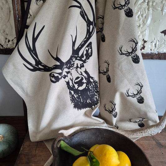 Beige fabric with black deer head design on a wooden surface with lemons.