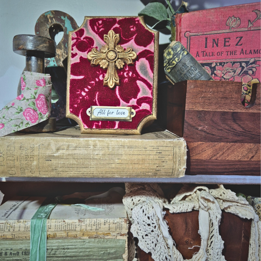 Decorative frame with floral design and cross on top of vintage books