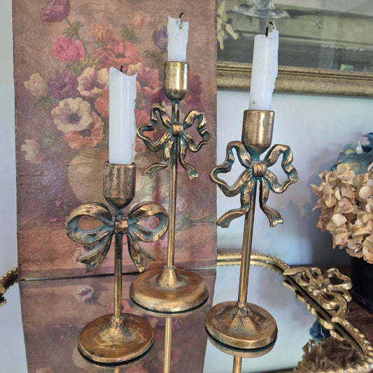 Decorative gold candle holders with white candles on a floral-patterned surface.