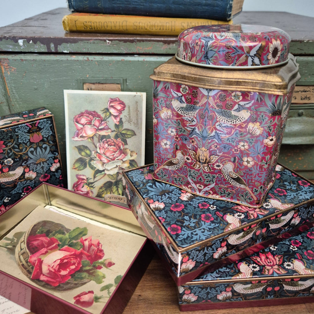 Vintage books with floral patterns and illustrations on a wooden surface with WIlliam Morris design