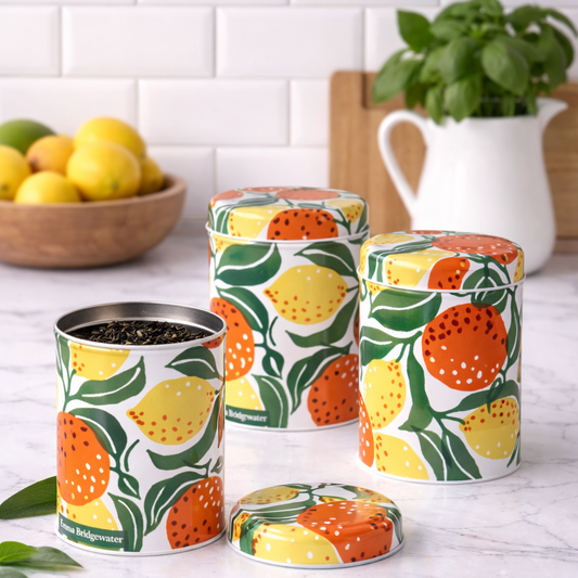 Set of 3 tin storage jars with fruit pattern on a kitchen counter.