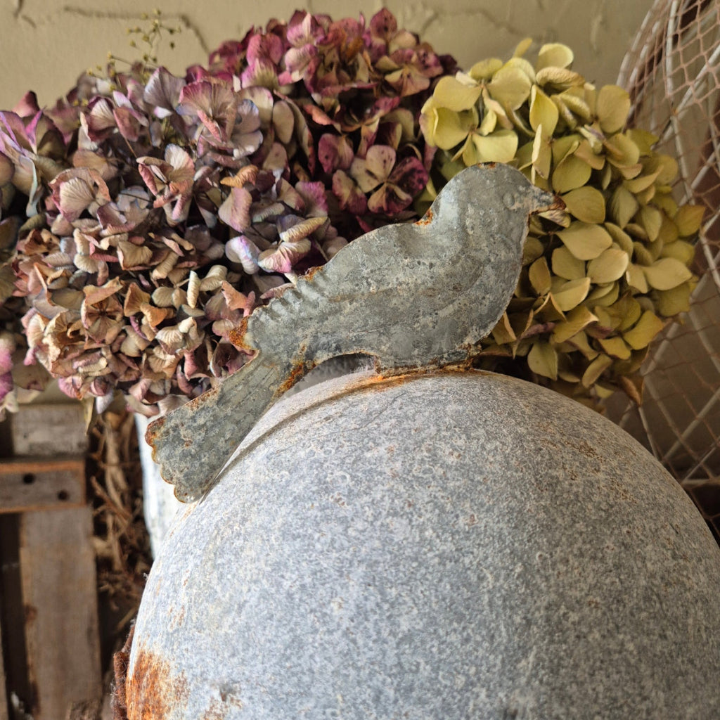 Decorative stone sculpture with dried hydrangea flowers on a neutral background
