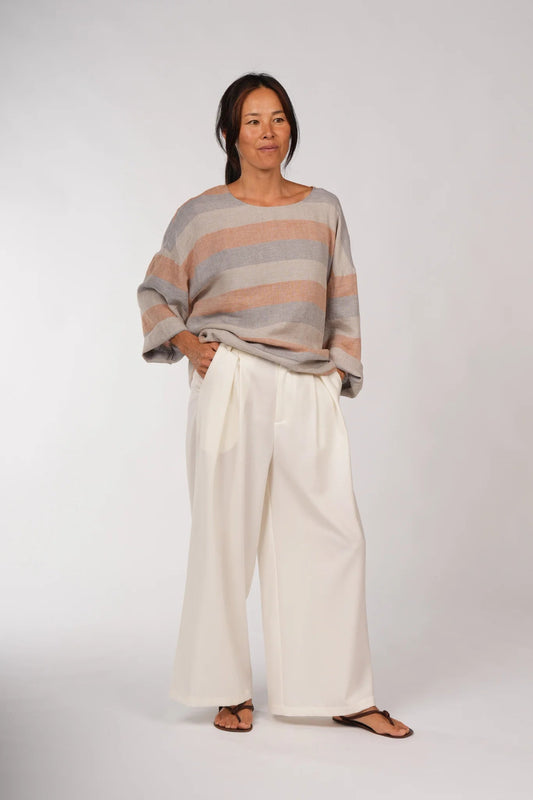 Woman wearing a striped sweater and wide-leg pants on a white background